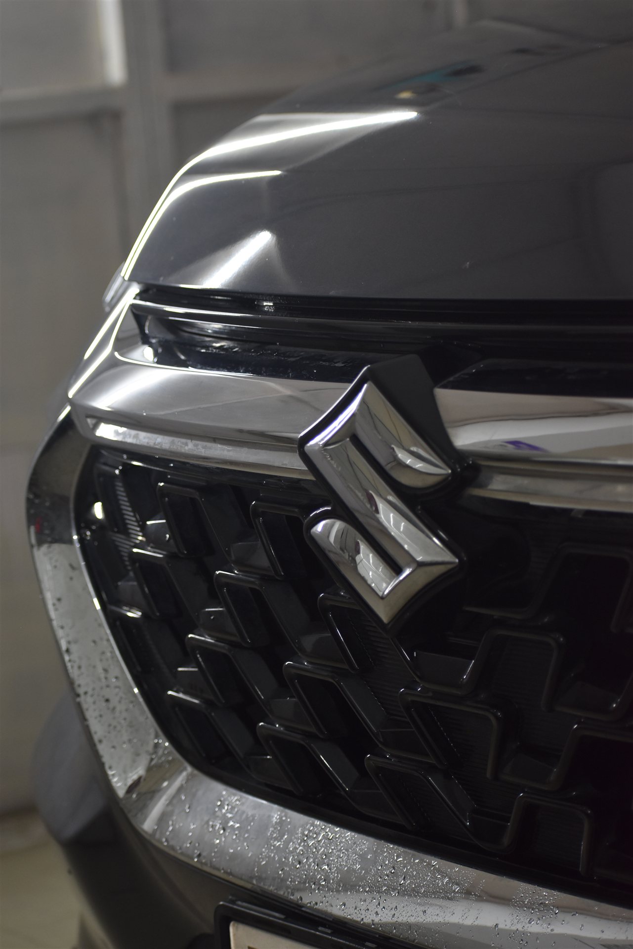 Water beads on glossy Suzuki chrome emblem and hood after ceramic coating